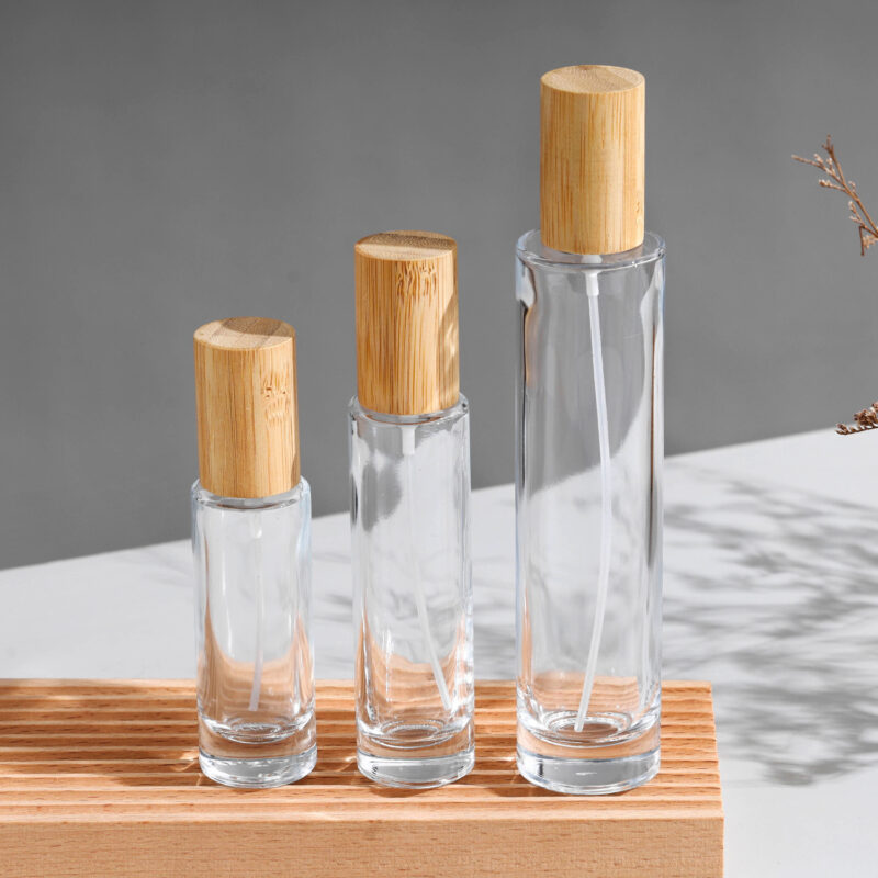 Slim cylindrical clear glass perfume bottles with bamboo caps and gold silver sprayers, various heights