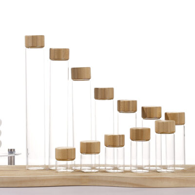 Borosilicate glass jars with screw-on wood caps in bamboo, acacia, and transfer-printed finishes, 12ml to 110ml